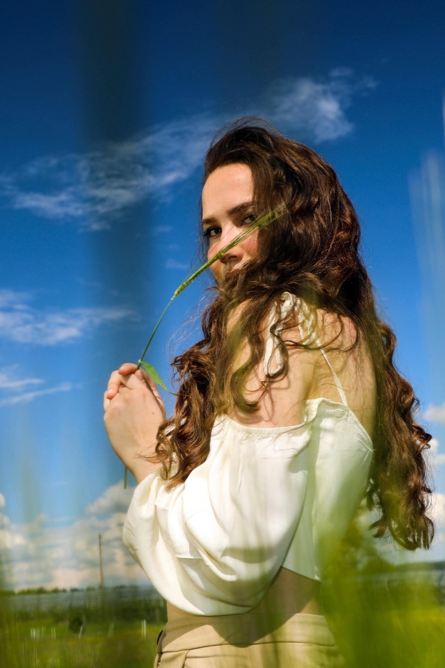 Милая девушка на поле на фоне голубого неба