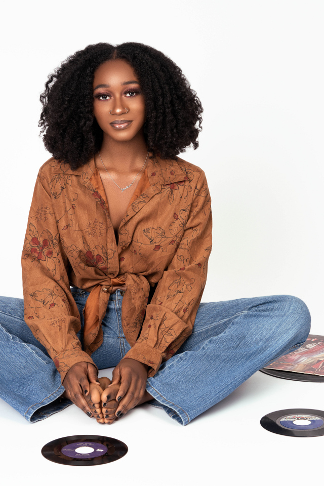 Темнокожая девушка сидит на белом фоне с пластинками