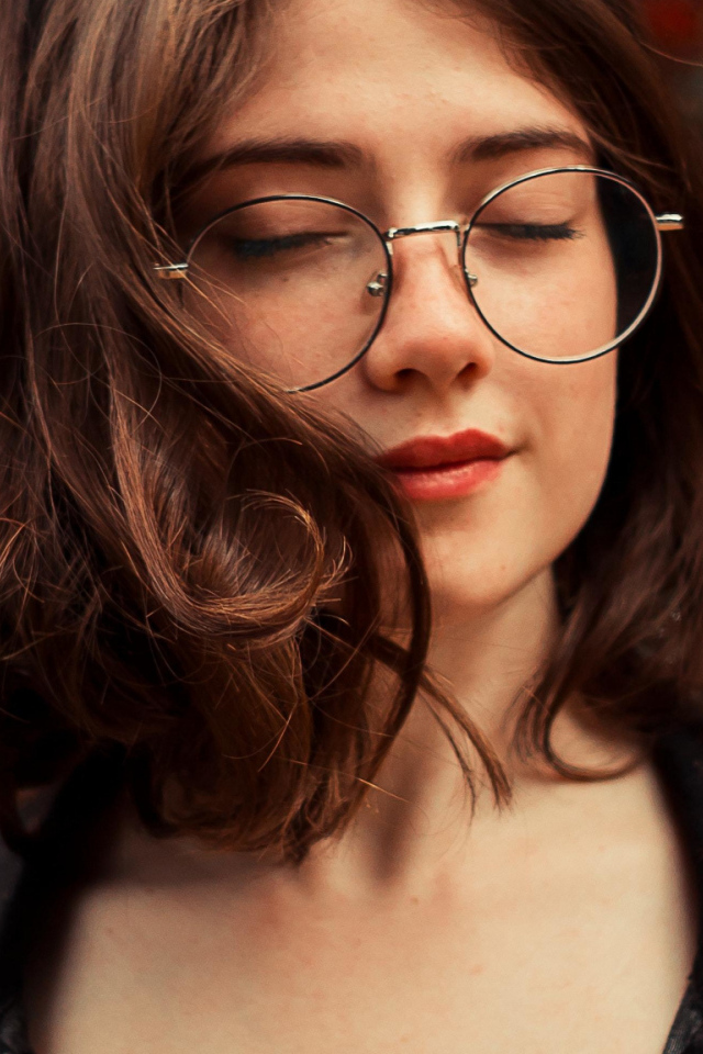 Мечтательная девушка в очках с закрытыми глазами