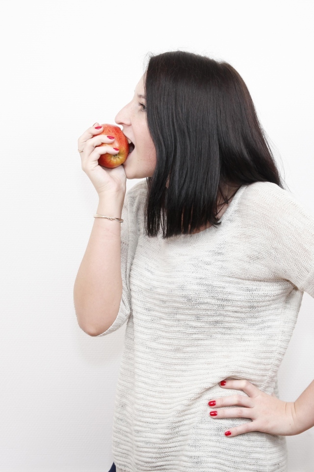Девушка кусает красное яблоко 