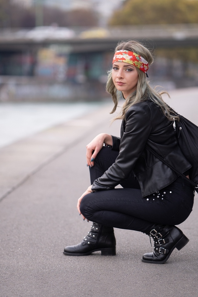 Девушка в черном костюме сидит на корточках