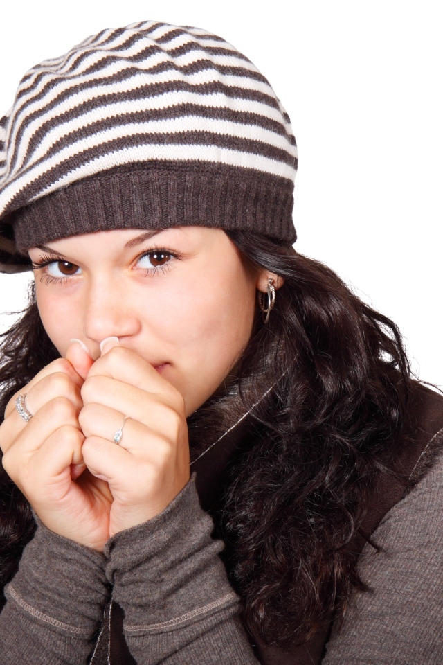 Девушка в теплой полосатой шапке на белом фоне