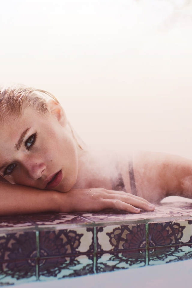 Девушка лежит в воде в бассейне