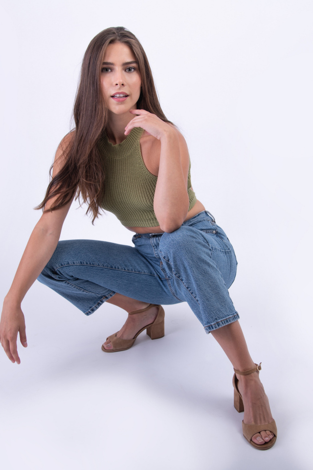 Девушка сидит на корточках на белом фоне