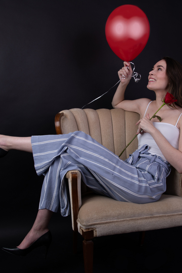 Девушка с шариком и розой сидит в кресле