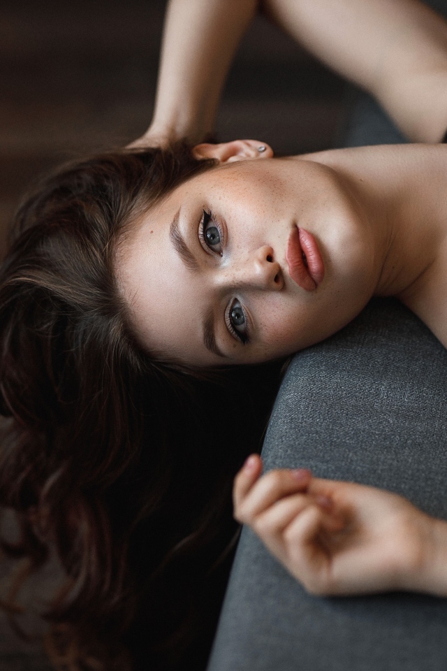 Девушка с длинными волосами лежит  на кровати