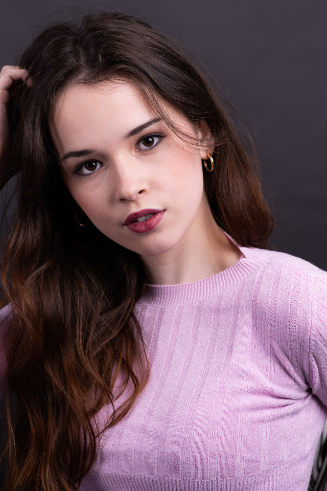 Длинноволосая шатенка в свитере с рукой в волосах