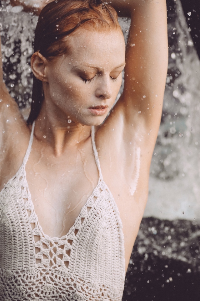 Рыжеволосая девушка в брызгах воды