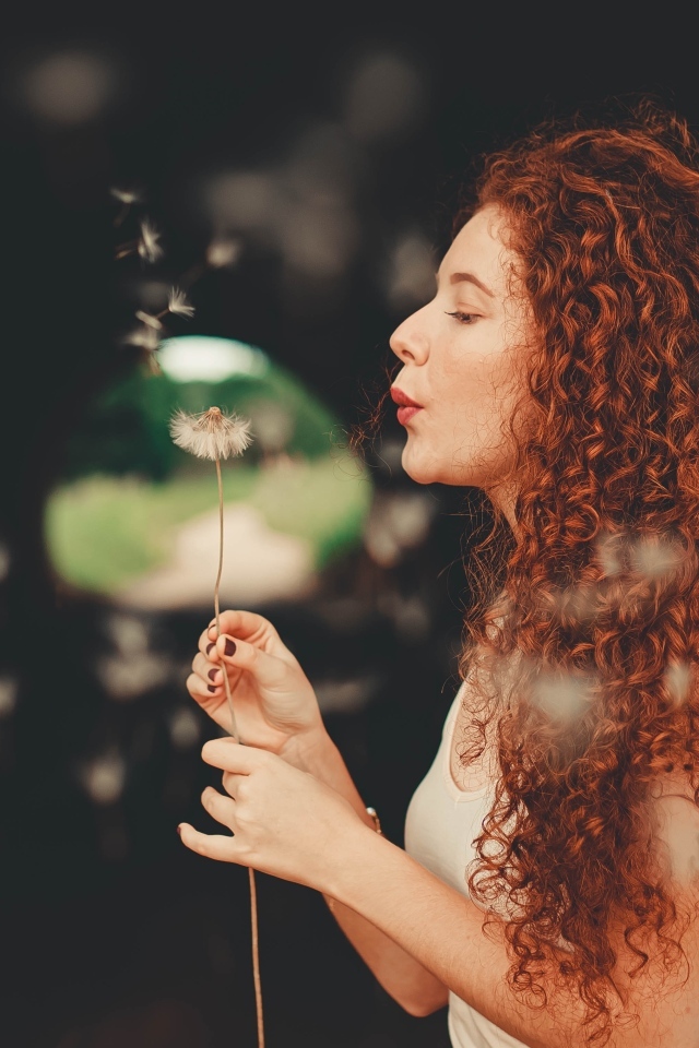 Рыжеволосая девушка с одуванчиком в руке
