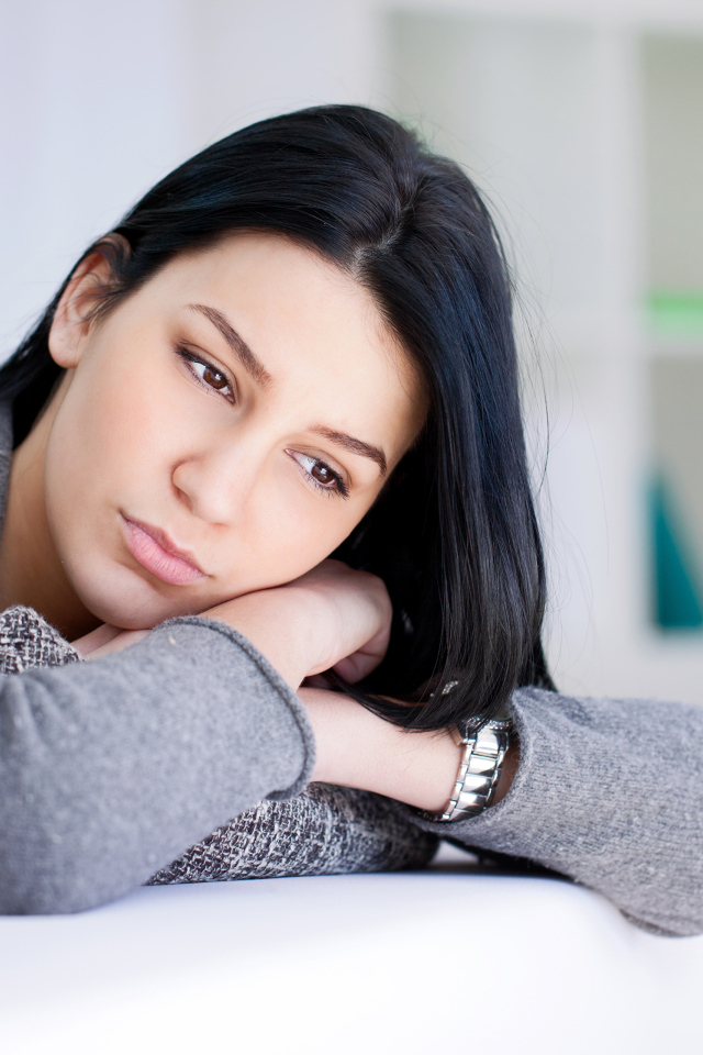 Грустная девушка брюнетка в серой кофте 