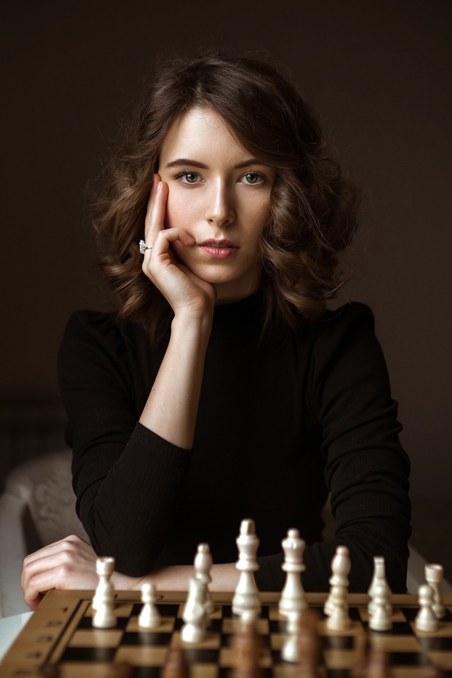 Умная молодая девушка играет в шахматы