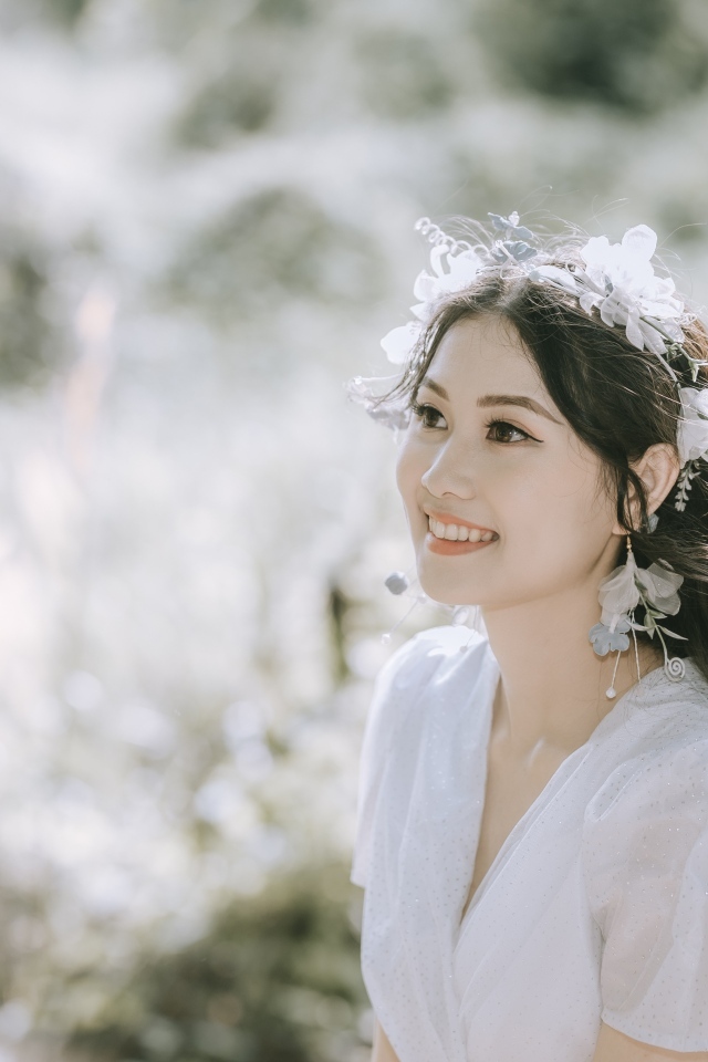 Улыбающаяся девушка азиатка в белом платье на поле