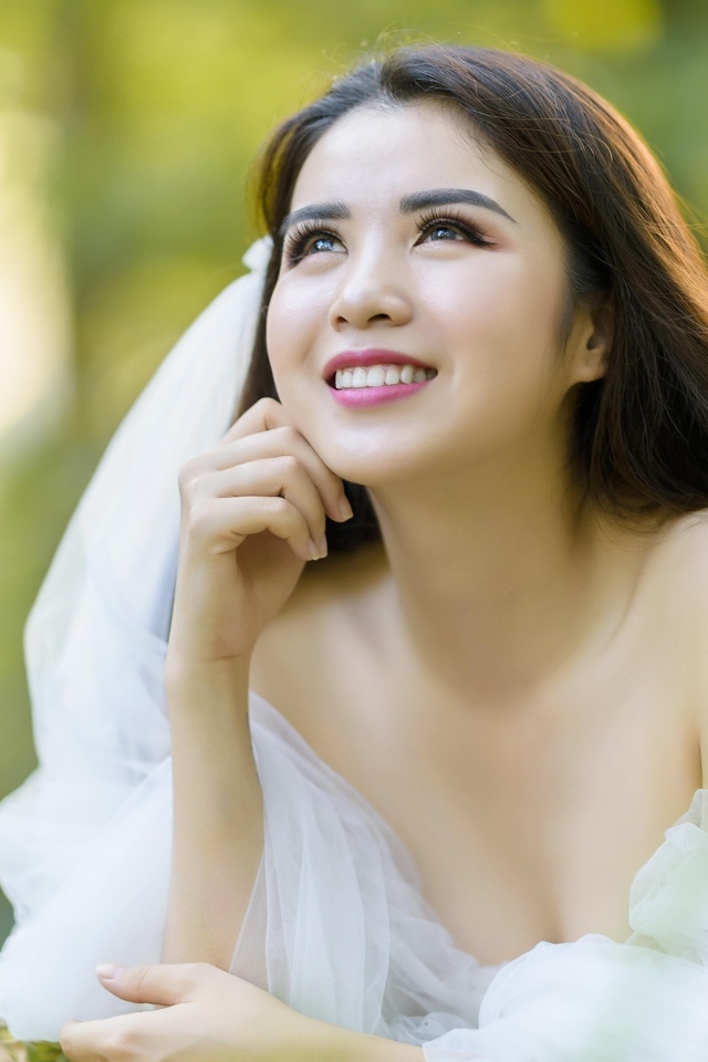 Улыбающаяся девушка азиатка в платье невесты