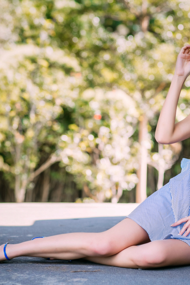 Улыбающаяся девушка азиатка сидит на асфальте