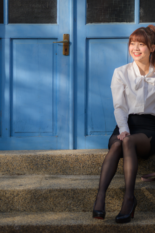 Улыбающаяся азиатка сидит на ступеньках