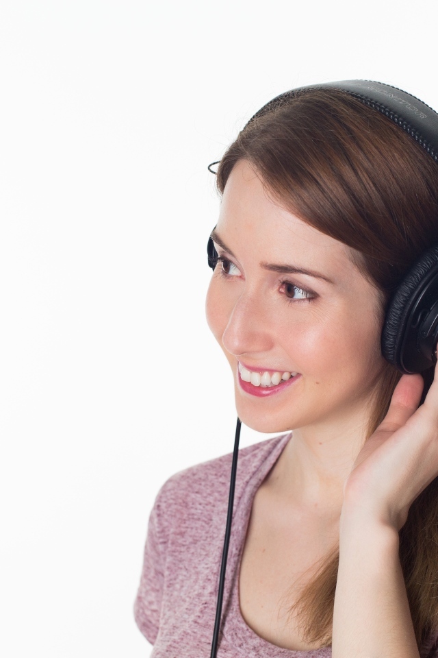 Улыбающаяся девушка в черных наушниках