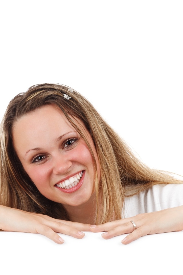 Улыбающаяся девушка сидит на белом фоне