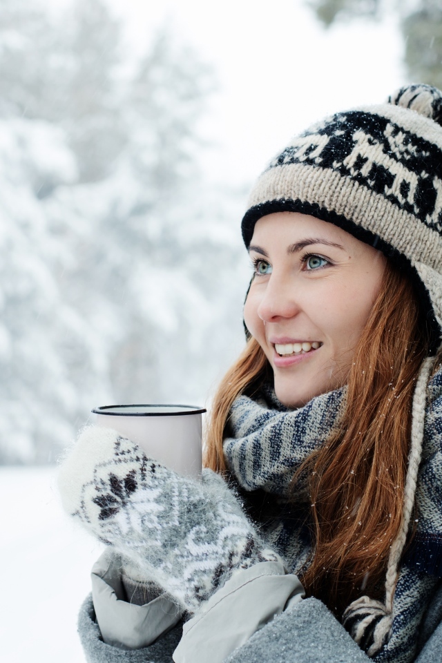 Улыбающаяся девушка с чашкой кофе зимой