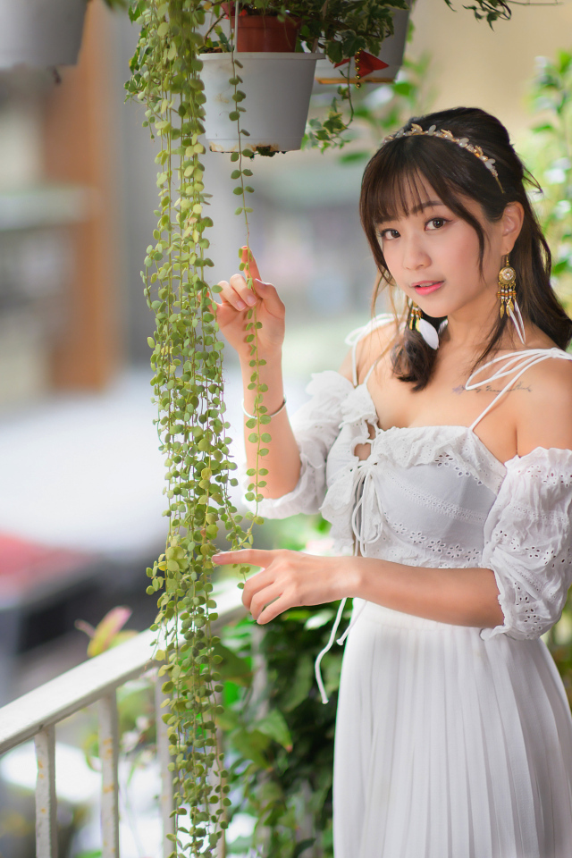 Молодая азиатка в белом платье у растений