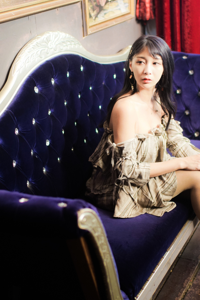 Молодая азиатка сидит на красивом диване