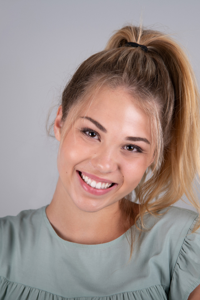 Молодая девушка блондинка на сером фоне