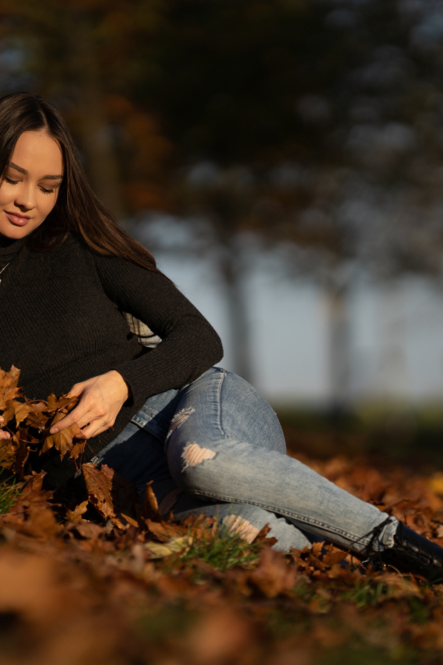 Молодая девушка лежит на сухих опавших листьях