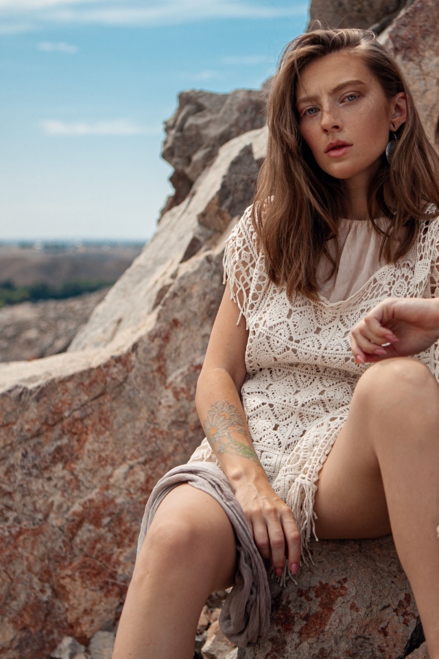 Молодая девушка сидит на камнях