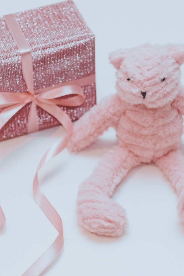 Подарок с розовой игрушкой на сером фоне