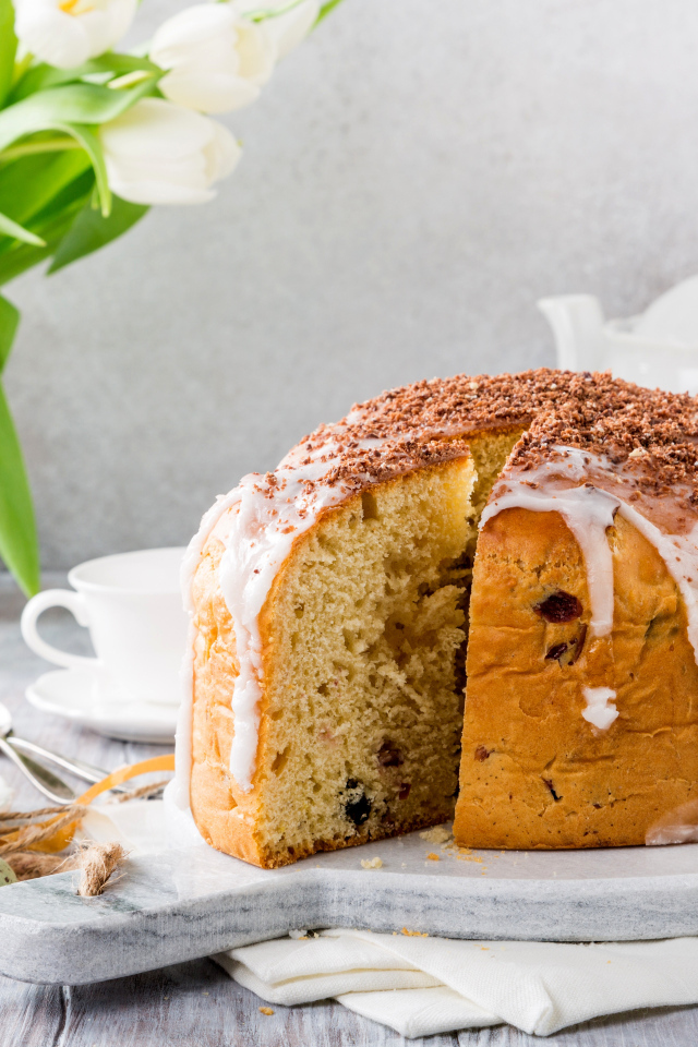 Пасхальный кулич на столе с букетом тюльпанов и сладостями