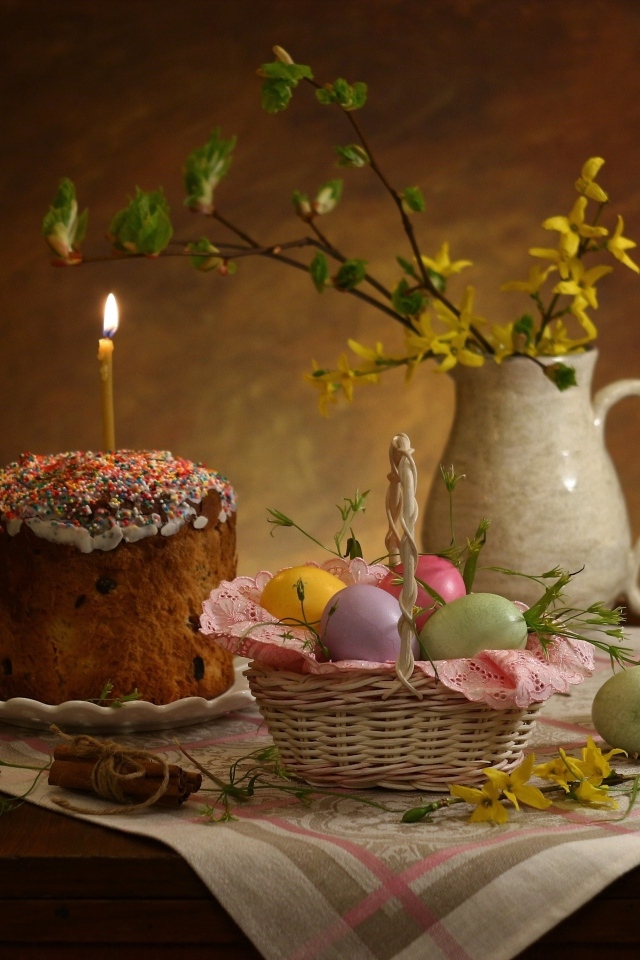Кулич со свечой и крашеными яйцами на столе на Пасху