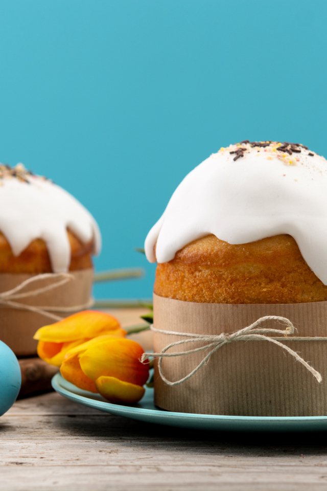 Пасхальные куличи с белой глазурью на столе с яйцами