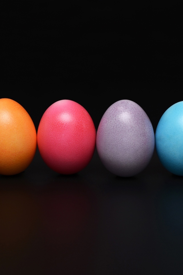 Разноцветные пасхальные яйца на черном фоне