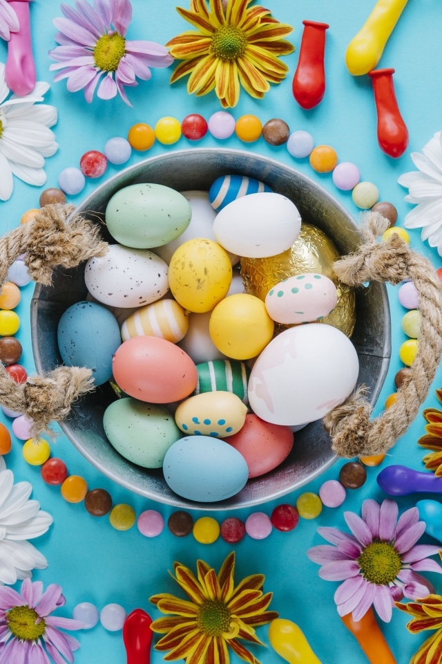 Разноцветные яйца с цветами на голубом фоне на Пасху