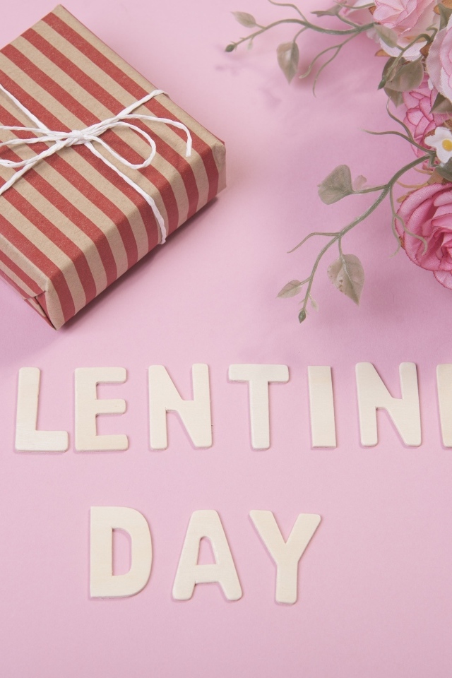 Цветы и подарок на розовом фоне на День Святого Валентина