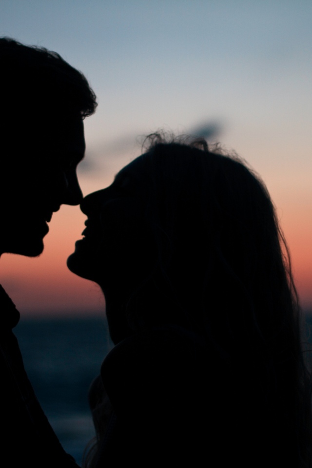 Влюбленная пара стоит на фоне заката в сумерках