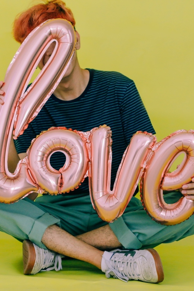 Мужчина держит шарики с надписью любовь