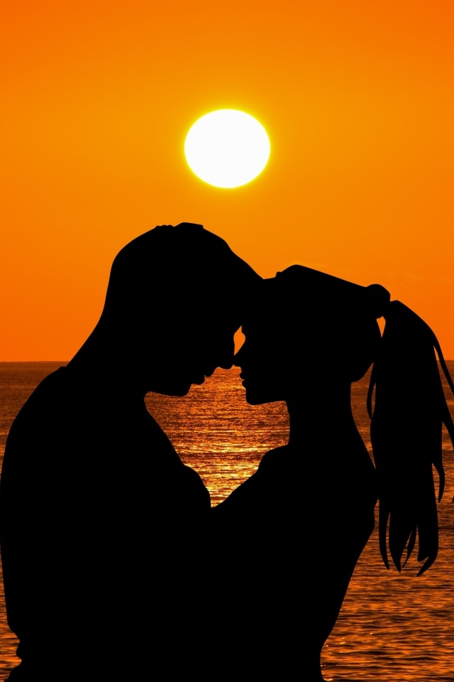 Влюбленная пара на закате солнца у моря