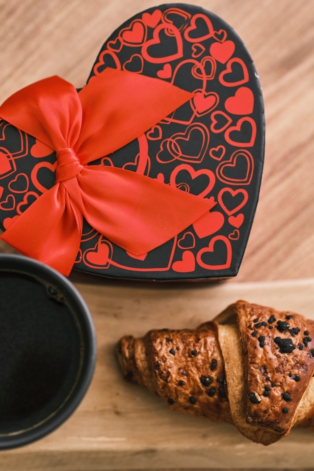 Коробка в форме сердца, кофе и круассан на столе