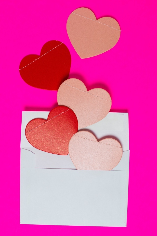 Сердечки с белым конвертом на розовом фоне