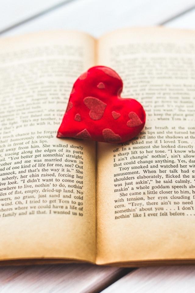 Маленькое красное сердце с книгой на столе