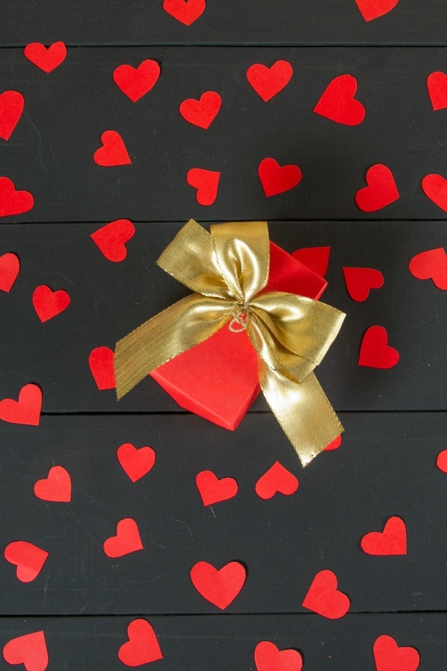 Много маленьких бумажных сердечек с подарком на столе