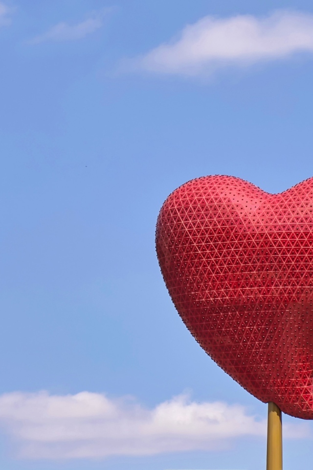 Красное сердце на палочке на фоне неба
