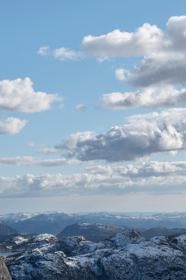 Мужчина стоит на краю скалы на фоне неба 