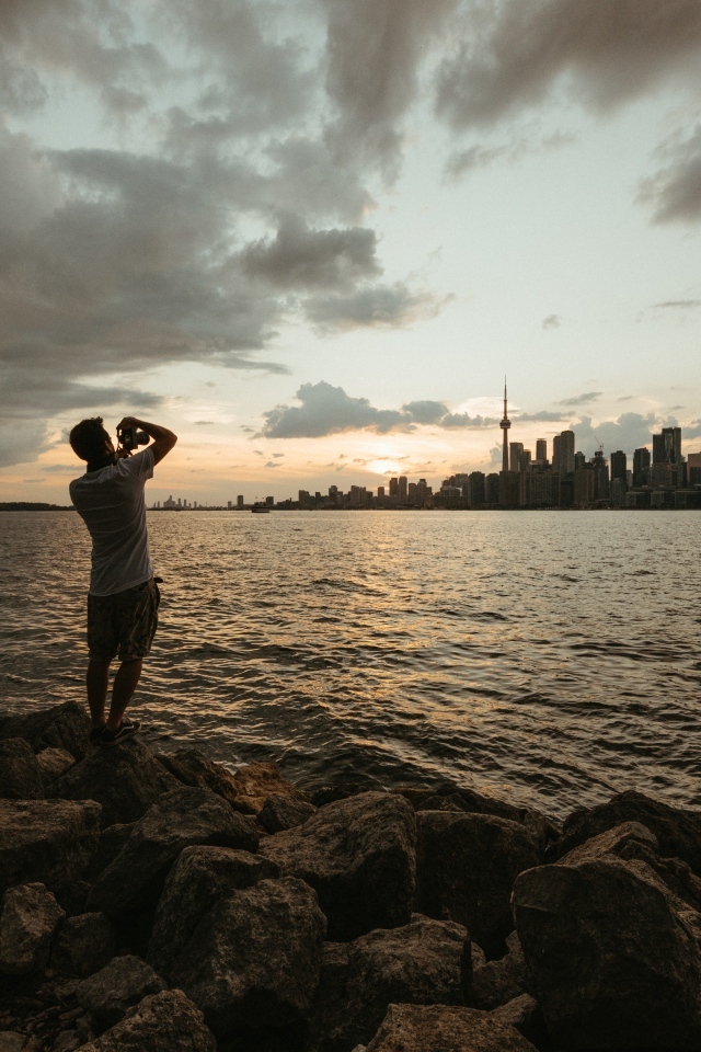 Мужчина делает фото города у моря