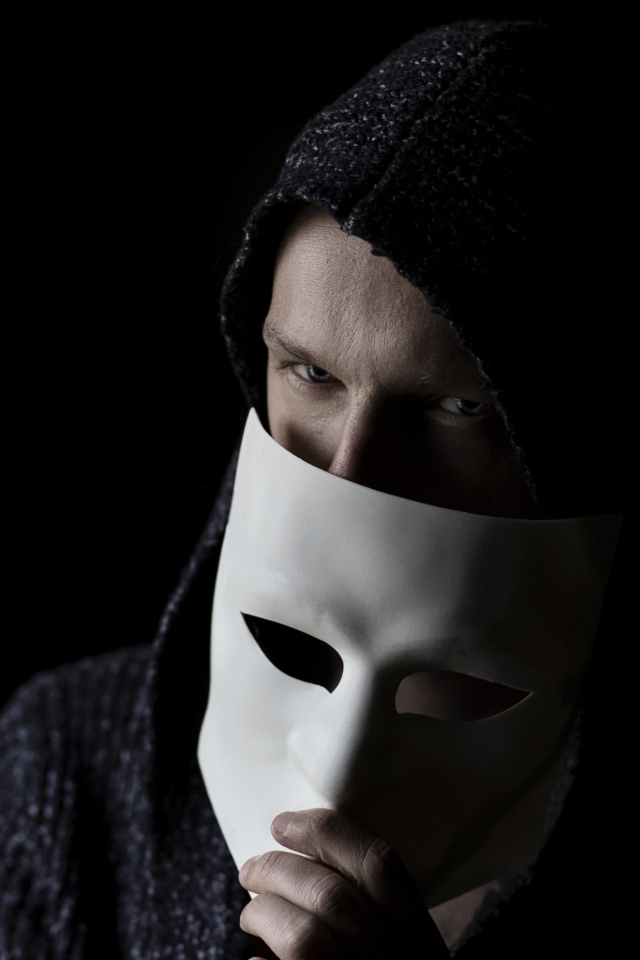 Мужчина с белой маской в руке на черном фоне
