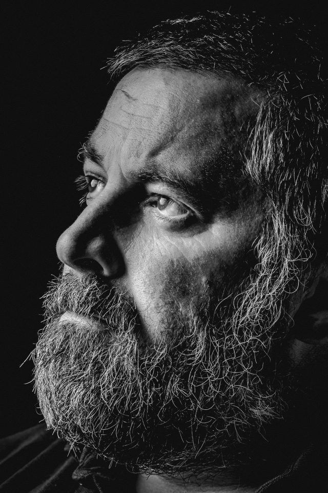 Пожилой мужчина с бородой на черном фоне