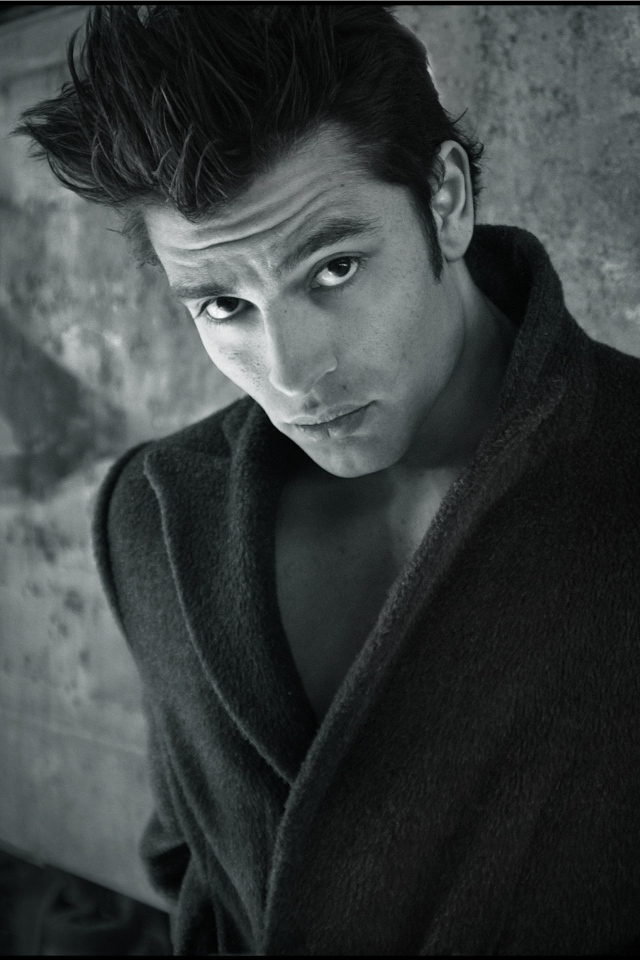 Красивый мужчина в черном пальто у стены