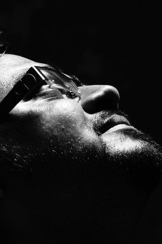 Мужчина в очках смотрит вверх на черном фоне