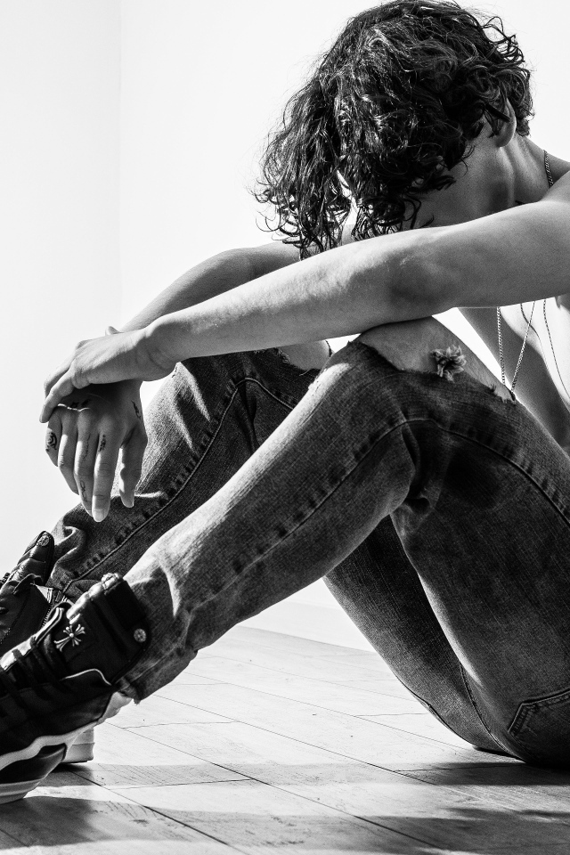 Грустный мужчина в джинсах сидит на полу