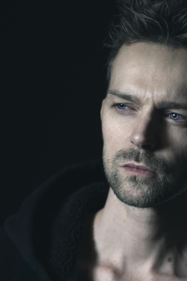 Серьезный голубоглазый мужчина на черном фоне